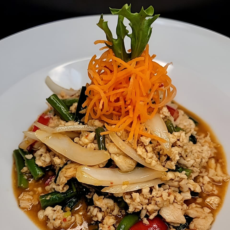 Nook's Thai dish with ground meat, vegetables, and shredded carrots on a white plate.