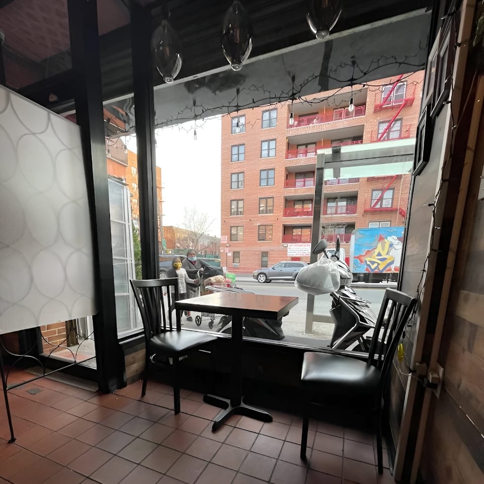 Interior view of Nook Thai restaurant with a small table and chairs by the window overlooking a city street.